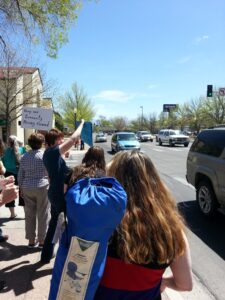 Grand Junction citizens protest in front of the Chamber of Commerce. The blue sign says "GJ Chamber endorses violence."