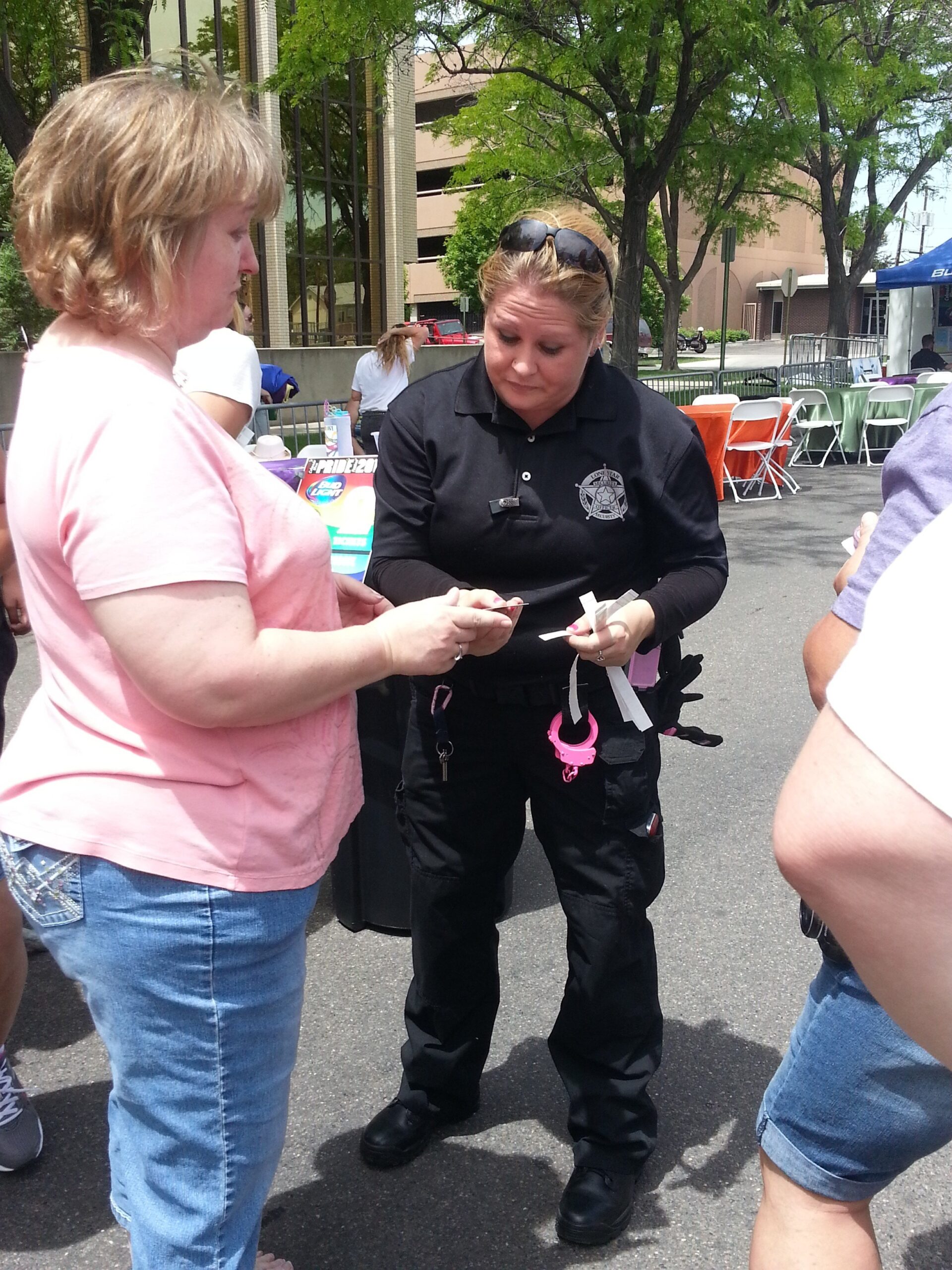 A female security guard sports pink handcuffs as she checks IDs to get into the beer garden at the 2014 Grand Junction Gay Pride Street Fest