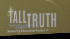 The leading "T" in Donahue's business logo is a crucifix in flames; the logo and cross appear in every slide, regardless if presentations at public schools